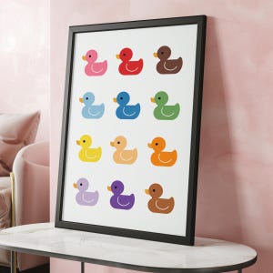 May include: A black framed print with a white background featuring 12 colorful rubber duckies arranged in a grid pattern.