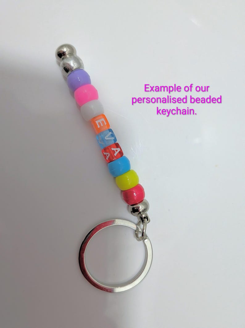 May include: A keychain featuring a silver metal ring and a vertical strand of colorful plastic beads. The beads include purple, pink, white, blue, yellow, and red, with the letters E, V, and A printed in white on the orange, blue, and red beads.