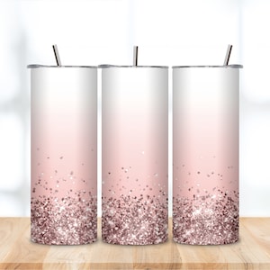 May include: Three stainless steel tumblers with lids and straws. The tumblers have a pink to white ombre design with a layer of glitter at the bottom.
