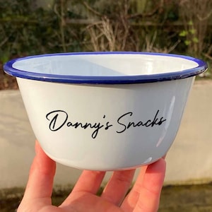 May include: White enamel bowl with a blue rim and the text "Danny's Snacks" in black script.