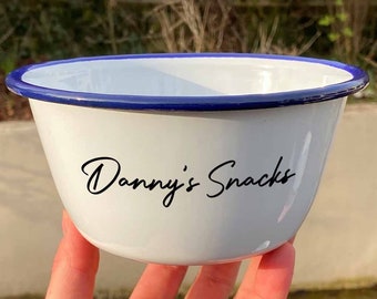 Puede incluir: Tazón de esmalte blanco con borde azul y el texto "Danny's Snacks" en letra negra.