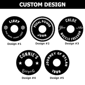 May include: Five different designs for custom bike wheel decals. Each design features a black circle with white text and graphics. The designs include "Lizzy", "Pedal Power John", "Chloe You Are Wheels Freedom", "Connie's Bicycle", and "Journey of Dylan 1986".