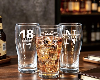 May include: Three clear glass pint glasses with custom white etched designs. The left glass reads 18 HAPPY BIRTHDAY RYAN. The center glass features a shield with the letter N and the text YOURNAME. The right glass displays the name NESTOR.