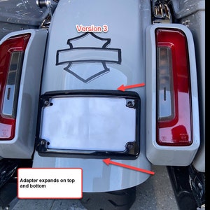Peut inclure: Un garde-boue arri&egrave;re de moto gris clair avec un cadre de plaque d'immatriculation noir. Le garde-boue pr&eacute;sente un embl&egrave;me noir et des feux arri&egrave;re rouges. Le texte "Version 3" est visible.