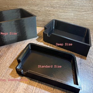 K&ouml;nnte beinhalten: Drei schwarze Aufbewahrungsbeh&auml;lter unterschiedlicher Gr&ouml;&szlig;e werden auf einer Holzoberfl&auml;che gezeigt. Die Beh&auml;lter sind mit "Mega Size", "Deep Size" und "Standard Size" beschriftet. Die Beh&auml;lter sind rechteckig und haben eine strukturierte Oberfl&auml;che.