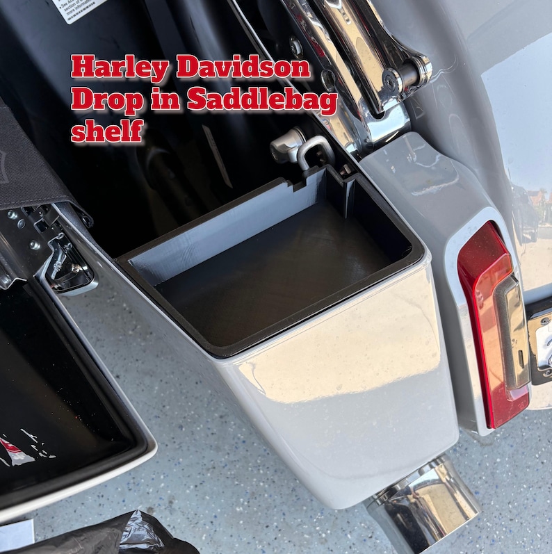 K&ouml;nnte beinhalten: Graues Harley Davidson Drop-in-Satteltaschenregal. Das rechteckige Regal hat einen schwarzen Innenraum und eine schwarze Umrandung. Das Motorradteil ist in einer wei&szlig;en Satteltasche mit rotem R&uuml;cklicht verbaut.