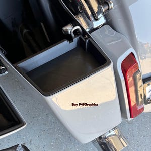 K&ouml;nnte beinhalten: Ein grauer Motorrad-Satteltaschen-Organizer mit rechteckiger Form. Der Organizer ist in einer wei&szlig;en Motorrad-Satteltasche installiert. Das Bild zeigt auch ein rotes R&uuml;cklicht und ein verchromtes Auspuffrohr. Der Text "Etsy 949Graphics" ist sichtbar.