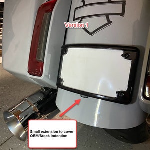 Peut inclure: Un garde-boue de moto gris clair avec un cadre de plaque d'immatriculation noir et un tuyau d'&eacute;chappement chrom&eacute;. Le garde-boue pr&eacute;sente un embl&egrave;me noir et blanc et un feu arri&egrave;re rouge. Le texte "Small extension to cover OEM/Stock indention" est inclus.