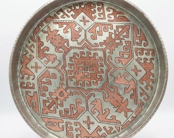 Antique round copper tray with traditional rug motif.