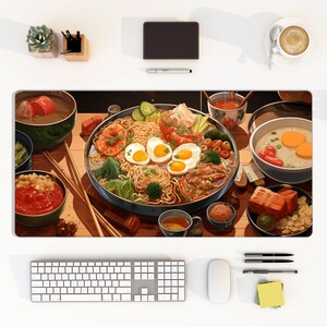 May include: A rectangular desk mat featuring a detailed illustration of a large bowl of ramen topped with three fried eggs, shrimp, broccoli, and sliced cucumbers, surrounded by smaller bowls of soup, side dishes, and wooden chopsticks.