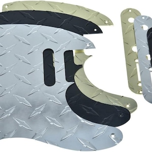 May include: Assortment of diamond plate guitar pickguards in silver, black, and gold colors. The pickguards have various shapes and sizes, with pre-drilled holes for mounting. The metal plates have a textured, non-slip surface.