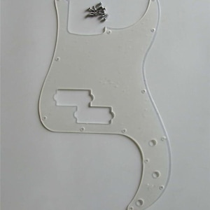 May include: A clear, white bass guitar pickguard with pre-drilled holes and cutouts for pickups. Includes a small pile of silver screws. The pickguard has a curved shape and is designed to fit a specific bass guitar model.