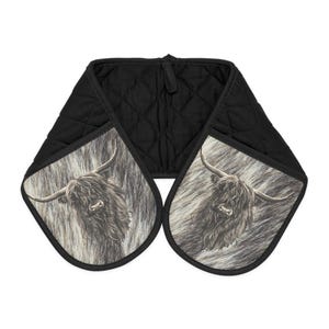 May include: Double oven glove with a Highland cow design. The black quilted glove features a black and white image of a Highland cow on each side. Designed to protect hands from heat when handling hot cookware in the kitchen.