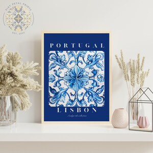 May include: A blue and white tile print with a floral design. The print is framed and has the text "PORTUGAL" and "LISBON - Azulejo tile collection" on it.
