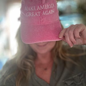 May include: A pink baseball cap with the text "Make America Great Again" embroidered in white.