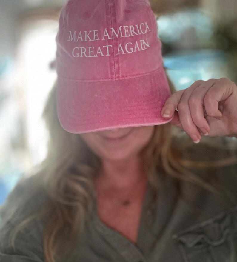 May include: A pink baseball cap with the text "Make America Great Again" embroidered in white.