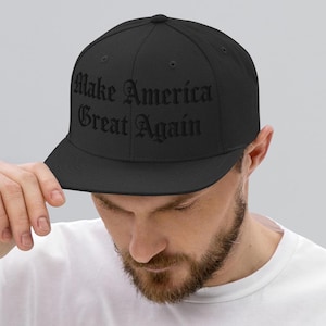 May include: A black fitted baseball cap with the text "Make America Great Again" embroidered in black.