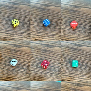 May include: Nine different coloured dice with various dot patterns. The dice are on a wooden surface.