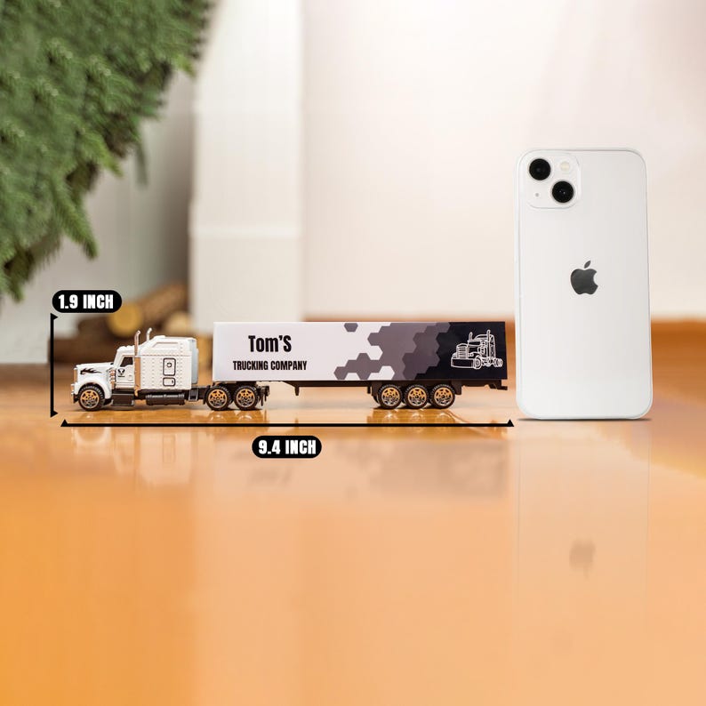 May include: White toy semi-truck and trailer with black and white camouflage pattern. The trailer says "Tom's Trucking Company". The truck is 9.4 inches long and 1.9 inches tall.