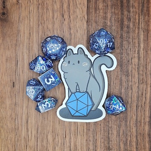 May include: A gray cat with a blue and white d20 die, surrounded by blue and white dice with black numbers.