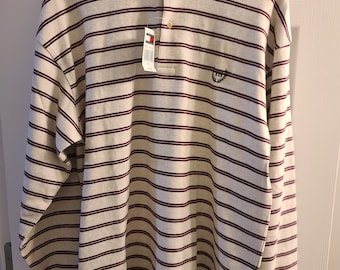 May include: Cream-coloured long-sleeved polo shirt with horizontal burgundy stripes. The shirt has a collared neckline, a three-button placket, and a small embroidered logo on the chest. A tag with the brand logo is attached.