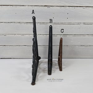 May include: Three vintage metal furniture legs are displayed against a white background. The legs are in different styles and colors: a black ornate leg, a black straight leg, and a brown tapered leg. The shop's name, "good vibe vintage", is at the bottom.