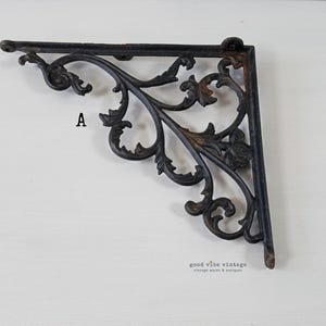 May include: Ornate black metal shelf bracket with a scrolling leaf design. The bracket is in an L-shape and features the letter "A". The bracket is a vintage item.
