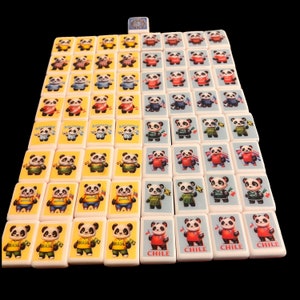 May include: A set of 72 dominoes featuring panda bears wearing football jerseys representing different countries. The dominoes are white with yellow edges and black dots. The pandas are wearing jerseys with the names of countries like "Brazil", "Chile", and "Argentina".