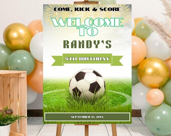 May include: A wooden easel displays a soccer-themed birthday party sign. The sign reads "Welcome to Randy's 9th Birthday" with a soccer ball on a green field. Balloons in gold, white, and green surround the sign.
