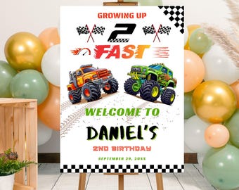 May include: A birthday party sign featuring a colorful monster truck theme. The sign reads "Growing Up Fast" with a large "2" and the name "Daniel's" in bold letters. The sign is decorated with checkered flags and monster truck illustrations.