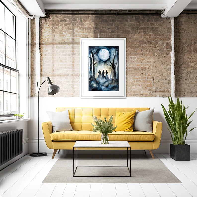May include: A watercolor painting of three figures walking through a forest under a full moon. The painting is framed in a white frame and hanging on a brick wall above a yellow sofa.