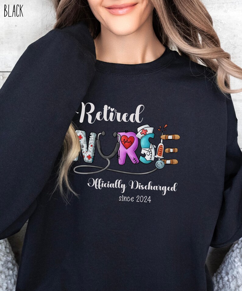 May include: Black sweatshirt with the text "Retired Nurse" in colorful letters with medical symbols. The text "Officially Discharged since 2024" is below the main text.