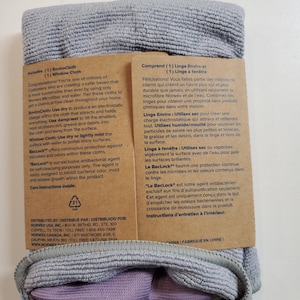 Puede incluir: Un paquete de cartón marrón con un paño de microfibra gris en su interior. El paquete incluye dos paños: un EnviroCloth y un Window Cloth. El texto del paquete dice "Includes (1) EnviroCloth (1) Window Cloth" y "Comprend (1) Linge Enviro et (1) Linge à fenêtre".