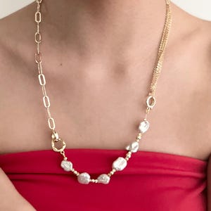 Peut inclure: Un collier dor&eacute; avec une combinaison de cha&icirc;nes et de perles blanches irr&eacute;guli&egrave;res. Le collier pr&eacute;sente un design unique, m&eacute;langeant diff&eacute;rentes textures et formes, cr&eacute;ant un bijou remarquable.