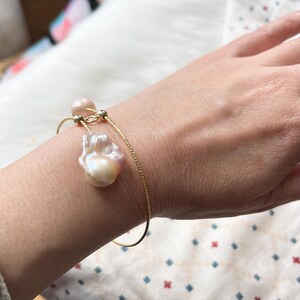 Peut inclure: Un bracelet en cha&icirc;ne dor&eacute;e avec deux perles baroques. Les perles sont de couleur rose clair et blanche.