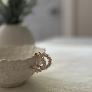 May include: A pair of gold hoop earrings with white pearl beads.