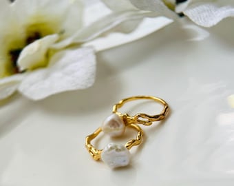 May include: Two gold rings with irregular, branch-like designs. Each ring features a white pearl, one round and one irregularly shaped.