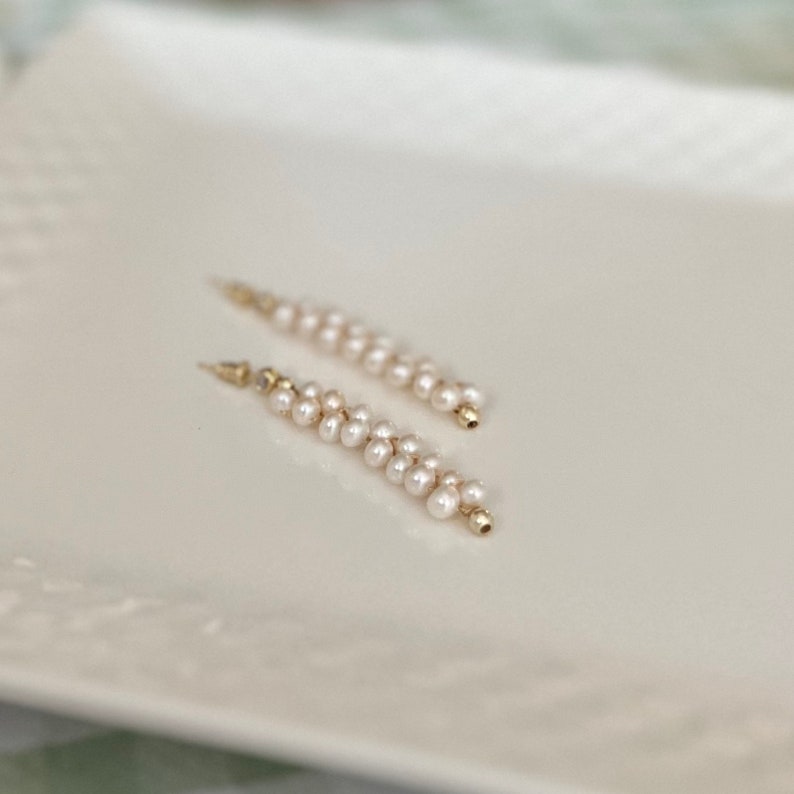 May include: A pair of long, delicate earrings with a gold base and a cascade of white pearls.