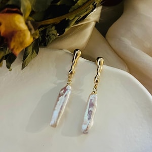 Peut inclure: Une paire de boucles d'oreilles en or avec de longues perles baroques blanches irrégulières qui pendent.