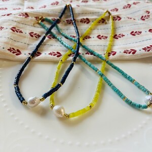 May include: Three necklaces with different colored beads and a pearl pendant. The necklaces are blue, yellow, and turquoise.