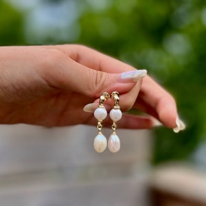 Peut inclure: Une paire de boucles d'oreilles pendantes en or avec deux perles blanches sur chaque boucle d'oreille.