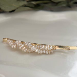 Puede incluir: Horquilla dorada adornada con peque&ntilde;as perlas de color blanco crema. La horquilla tiene un dise&ntilde;o sencillo y elegante, con las perlas agrupadas en la parte superior. La horquilla mide aproximadamente 7.6 cm de largo.
