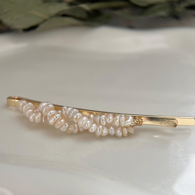Puede incluir: Horquilla dorada adornada con peque&ntilde;as perlas de color blanco crema. La horquilla tiene un dise&ntilde;o sencillo y elegante, con las perlas agrupadas en la parte superior. La horquilla mide aproximadamente 7.6 cm de largo.