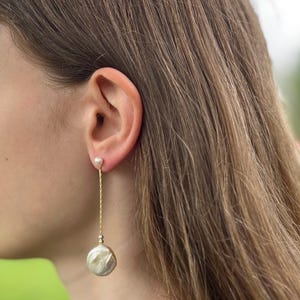 May include: A pair of gold chain earrings with a small pearl at the top and a larger, round pearl at the bottom.