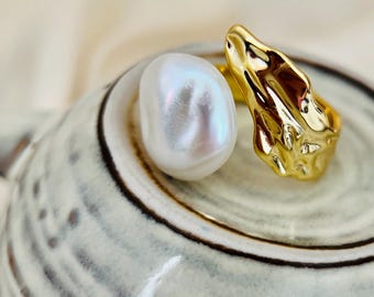 May include: Two gold rings, one with a textured, abstract design and the other with a large, white pearl.