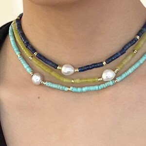 May include: A layered necklace with turquoise, yellow, and blue beads. The necklace features three large white pearls.