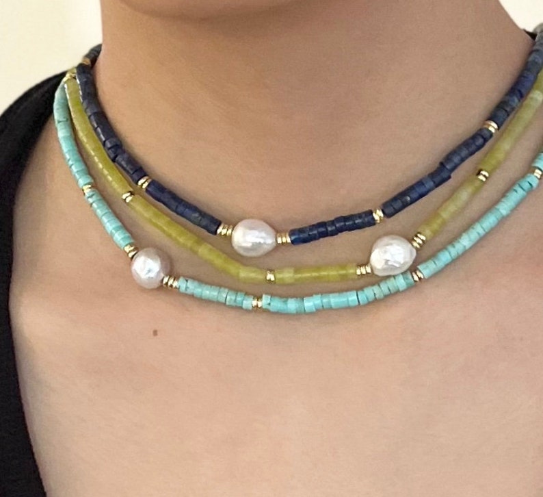May include: A layered necklace with turquoise, yellow, and blue beads. The necklace features three large white pearls.