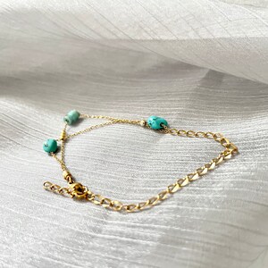 May include: A gold chain bracelet with turquoise beads. The bracelet has a lobster clasp closure.