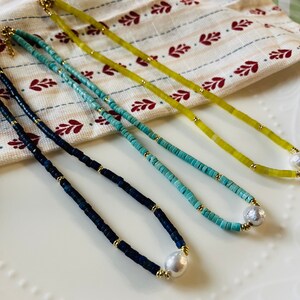 May include: Three necklaces with different colored beads and a pearl pendant. The necklaces are blue, turquoise, and yellow.