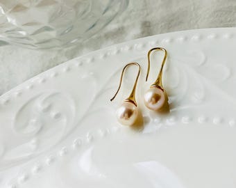 May include: A pair of gold dangle earrings with a single pearl on each earring.